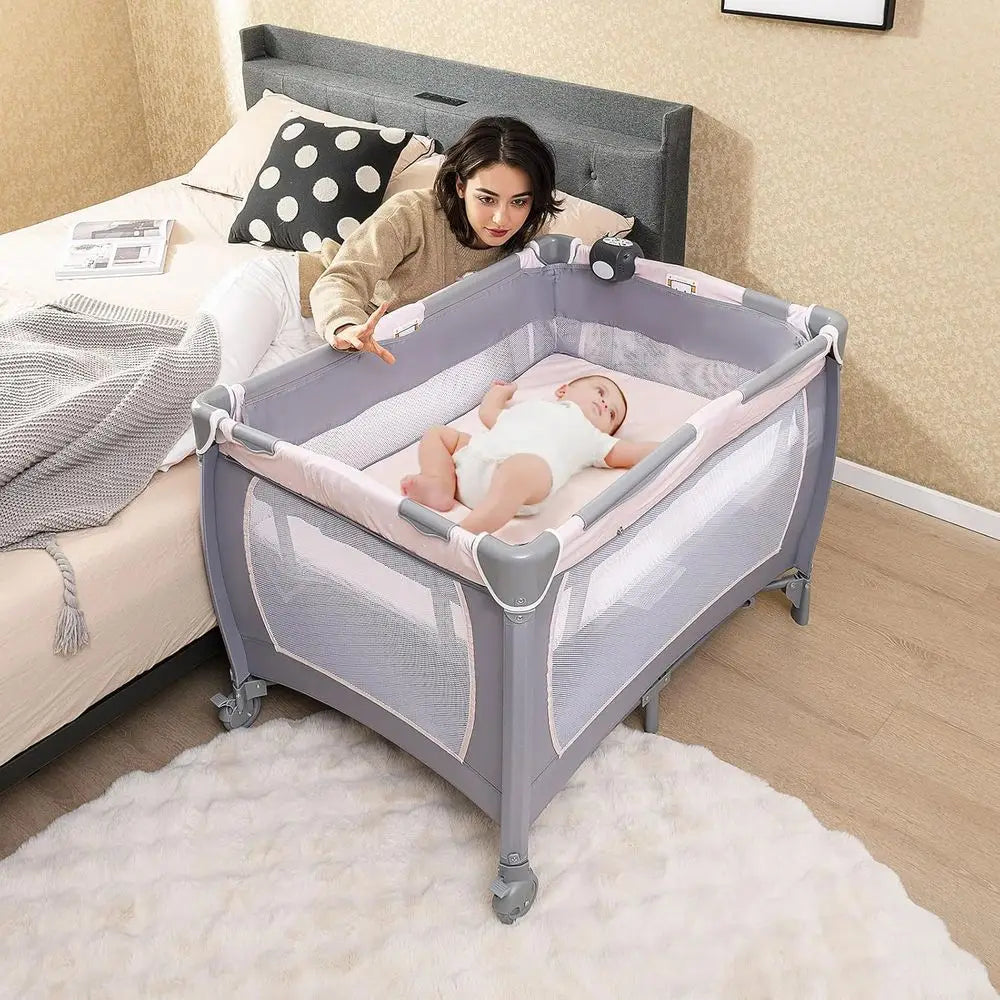 Portable Baby Playard with Bassinet, Cradle, Toys, Diaper Storage, and Changing Station in Pink